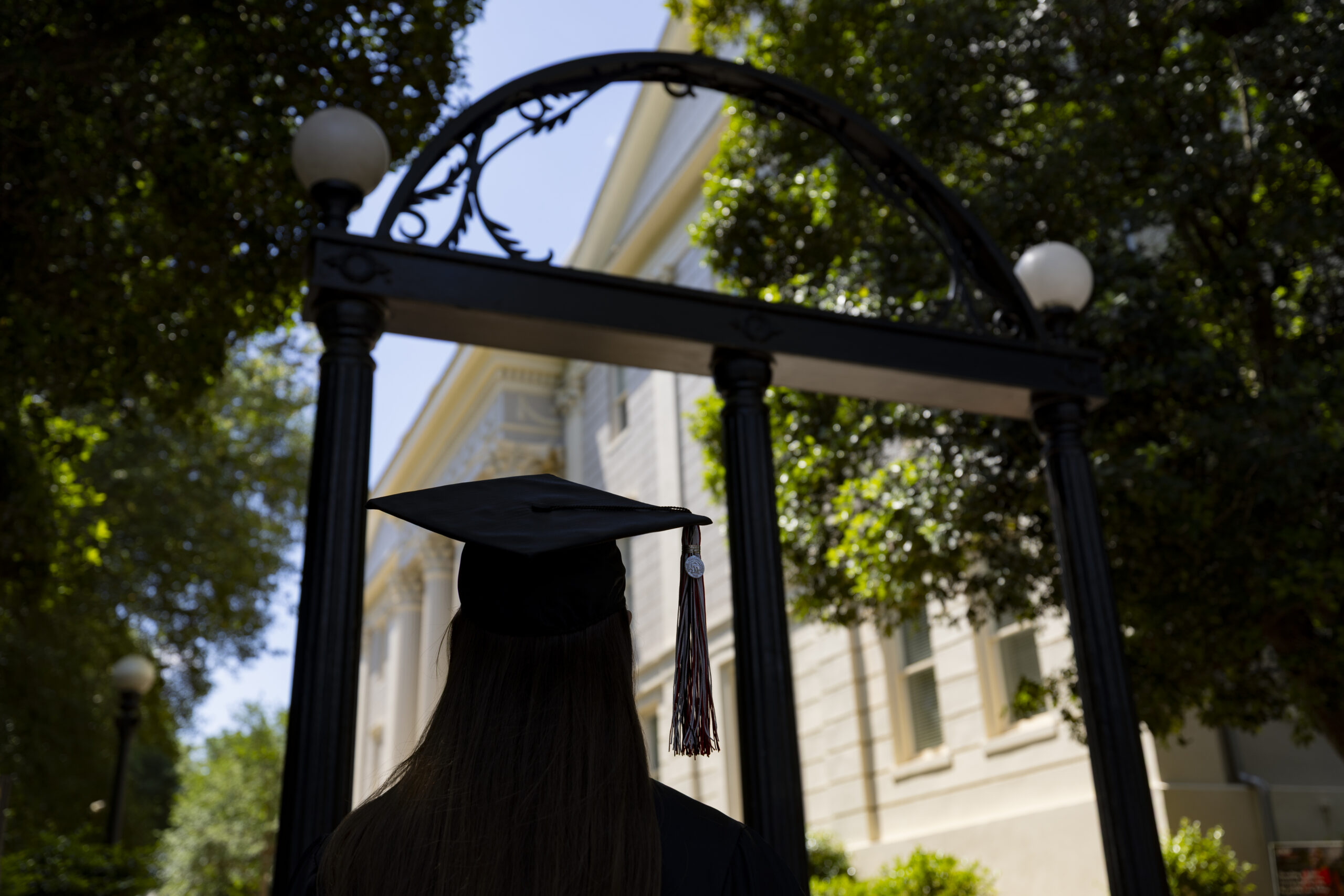 A student walks towards the arch in her cap and gown during commencement week.